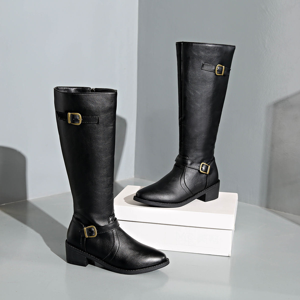 Delia Knee-High Boots in Black — front view of the leather upper and buckle straps